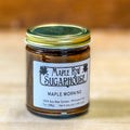 Jar of Maple Row Sugarhouse candle on a wooden surface